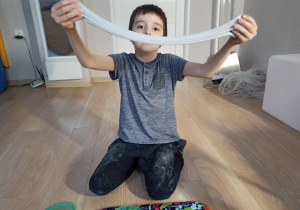 Chłopiec ćwiczy z pomoca masy plastycznej slime.
